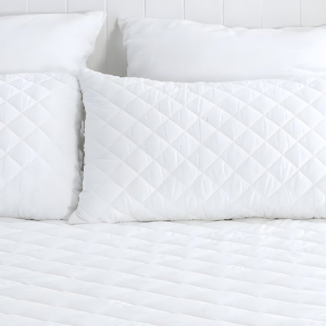 Full view of a white diamond quilted mattress protector styled neatly in a bright, modern bedroom