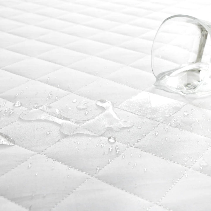 Water droplets beading on the surface of a white diamond quilted pillow protector demonstrating water resistance