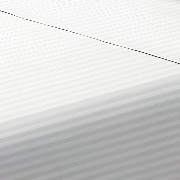 Close-up perspective of the smooth satin stripe weave of a crisp white cotton rich fitted sheet