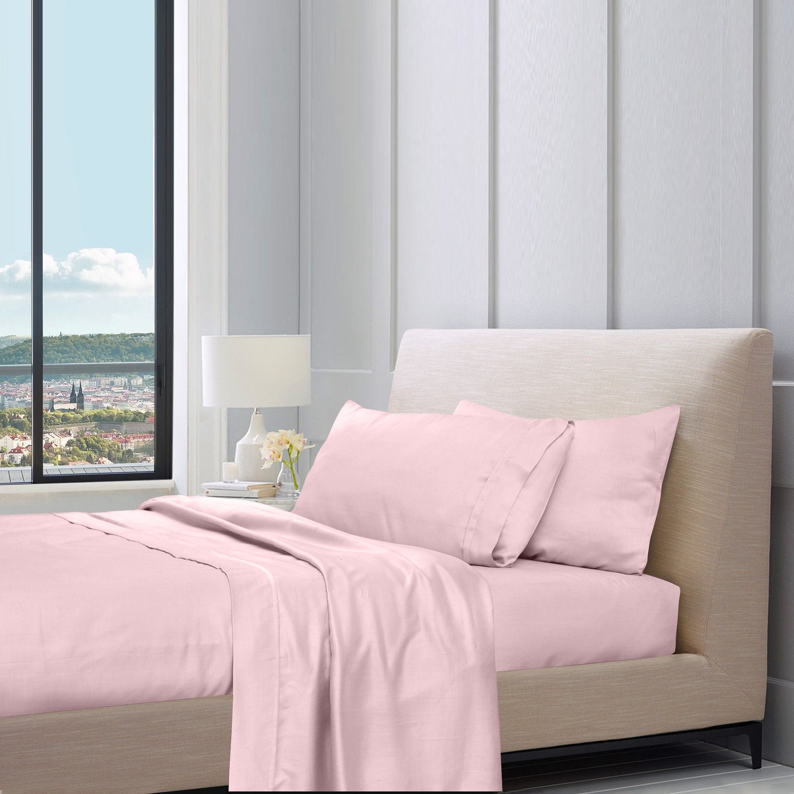 Baby pink cotton sheet set styled on a bed with pillows in a modern bedroom