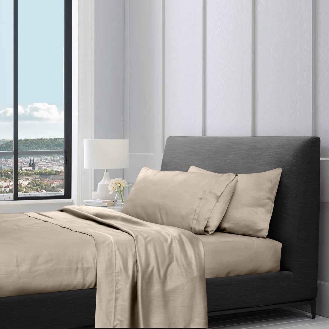 Beige cotton sheet set neatly folded and stacked on a bed