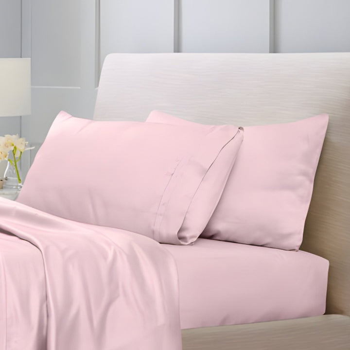 Overhead view of blush pink cotton sheet set with folded top sheet and pillowcases