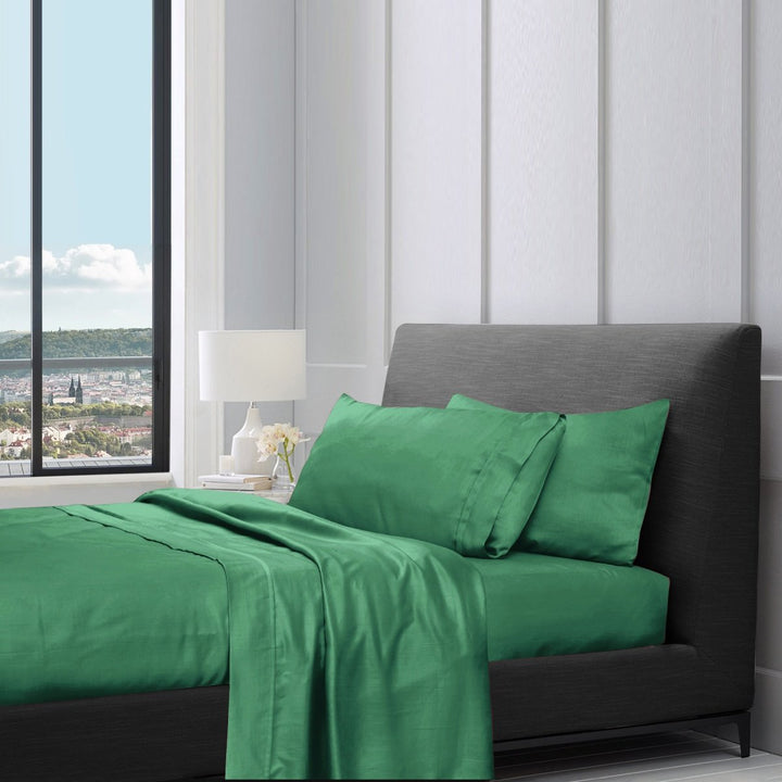 1200TC pure cotton sheet set in brunswick green styled on a bed with pillows