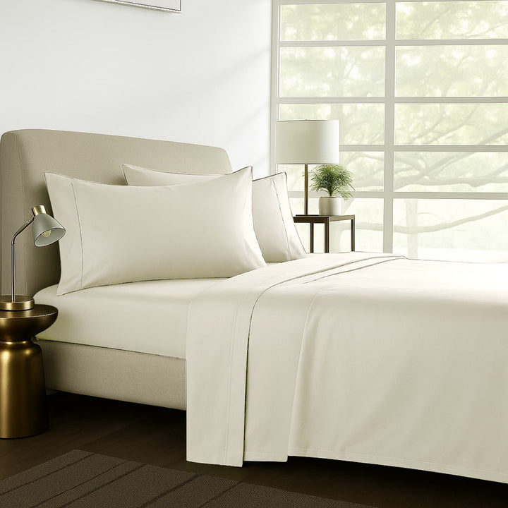 Pure soft cotton sheet set in cream styled on a bed in a warm-toned bedroom
