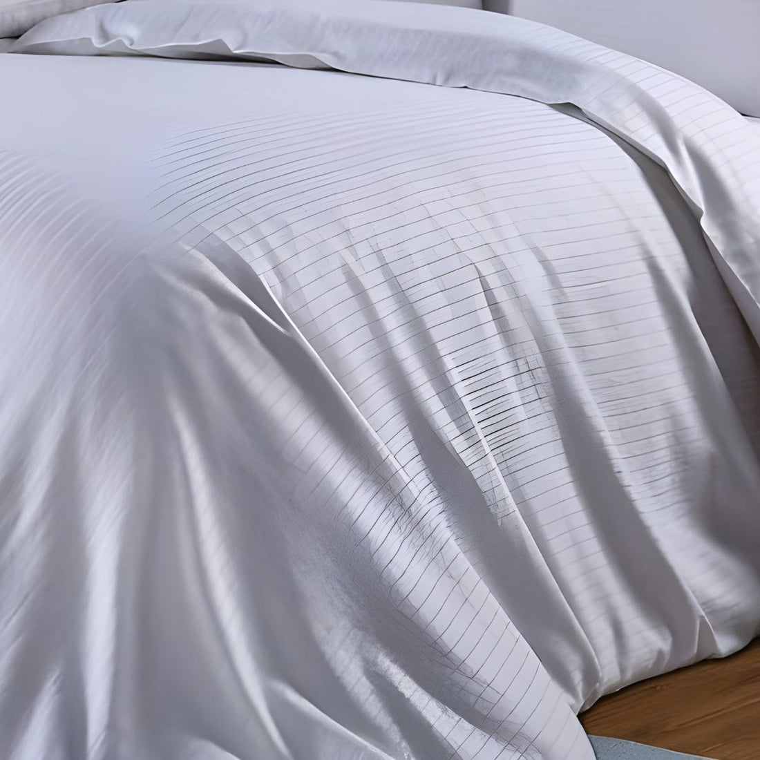 Side perspective of draped white hotel-style stripe duvet cover highlighting textured fabric folds