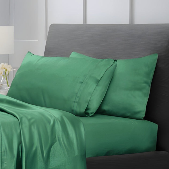 Brunswick green bed sheets draped over a bed near a window with city view