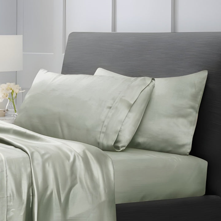 Overhead view of sage green cotton sheet set with folded top sheet and pillowcases
