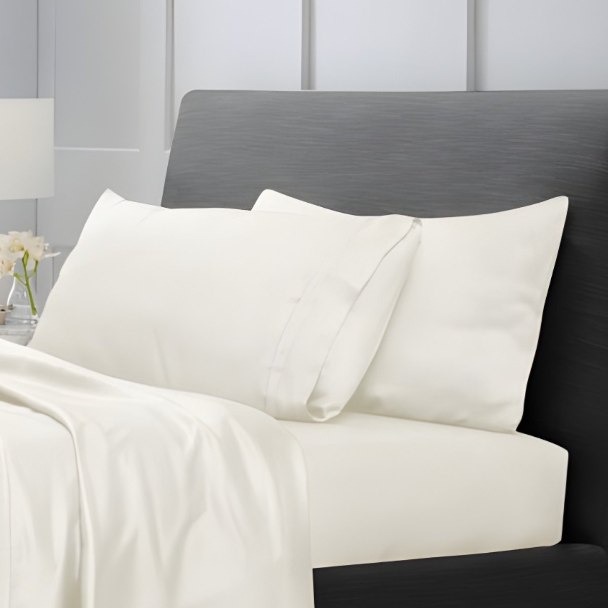 Cream bed sheets draped over a bed near a window with city view