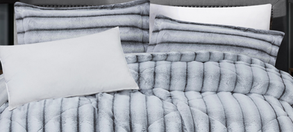 Close-up of textured channel-carved geometric faux fur fabric showing thick, soft ribbed folds.