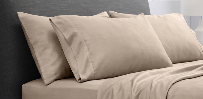 Overhead view of beige cotton sheet set with folded top sheet and pillows