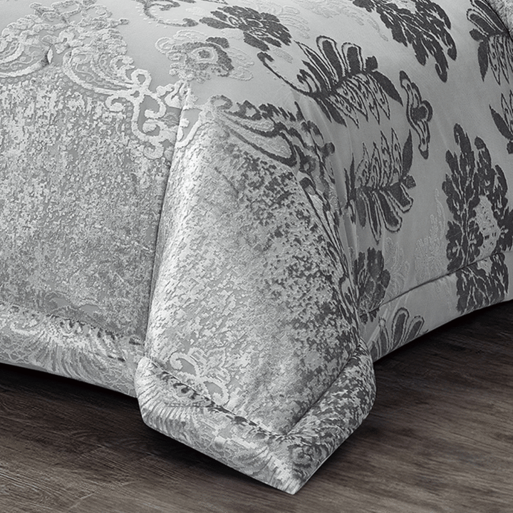 Full view of silver floral damask comforter set arranged with coordinated shams and accent cushions
