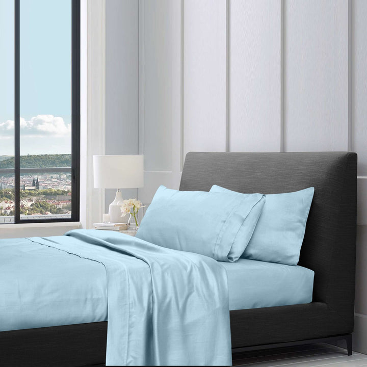 Light blue cotton sheet set styled on a bed with pillows in a modern bedroom