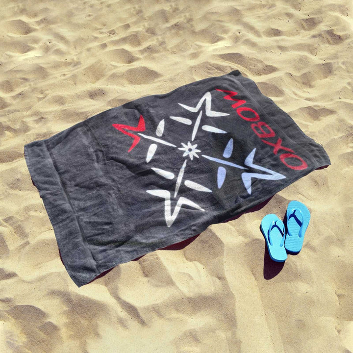 Oxbow black compass towel on sand