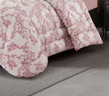 Full front view of a blush pink floral jacquard comforter and matching pillow shams in an elegant bedroom
