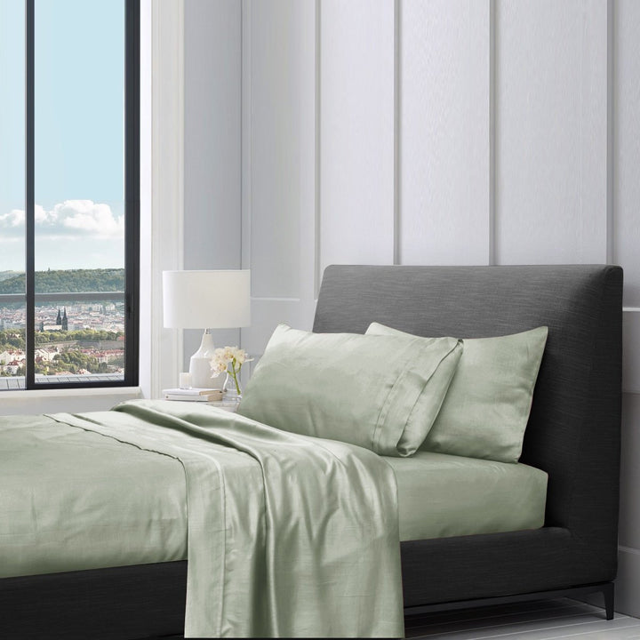 1200TC pure cotton sheet set in sage green styled on a bed with pillows