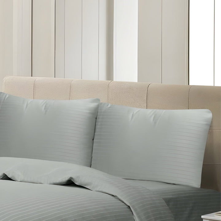 Full view of silver striped duvet cover and matching pillowcases on a luxury upholstered bed.