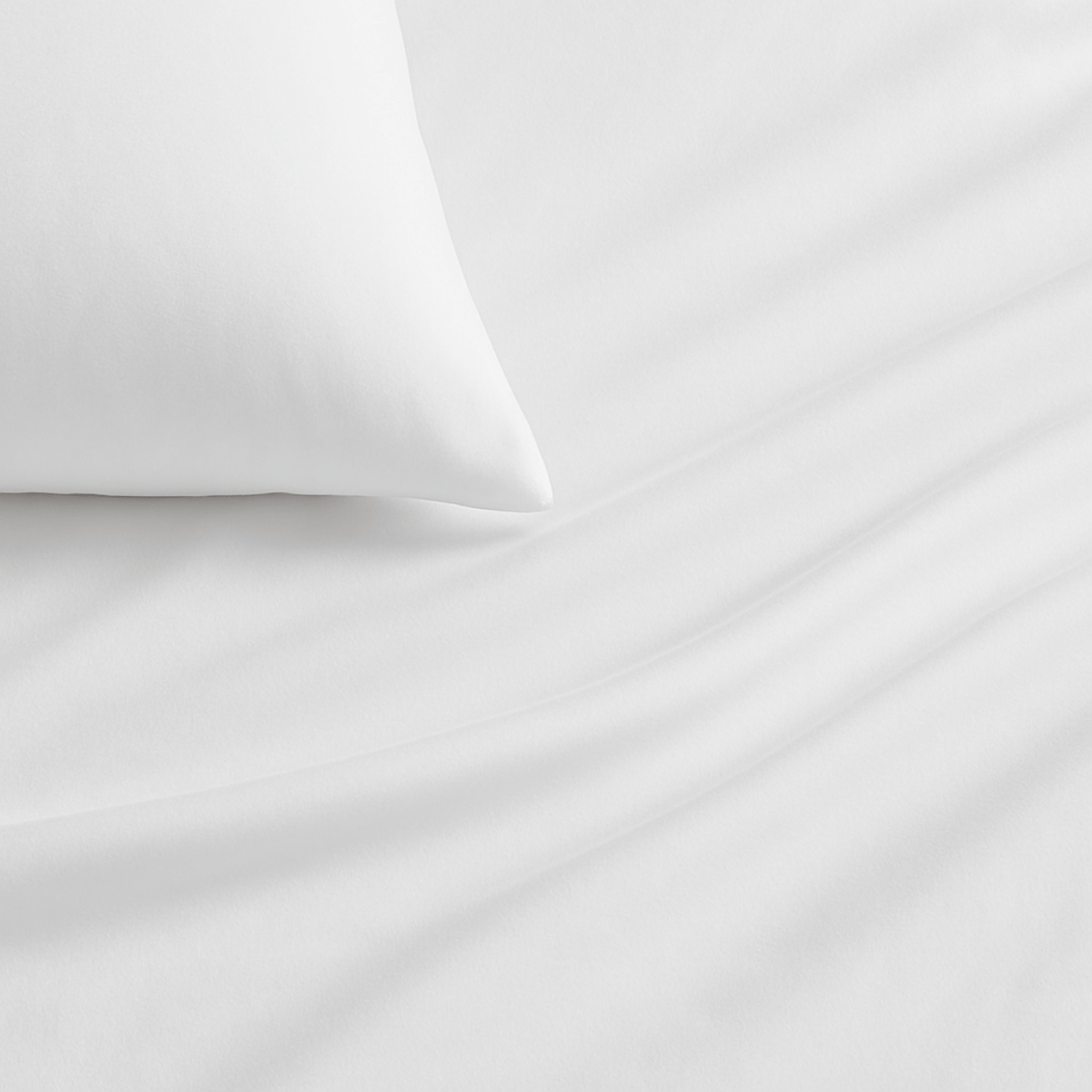 White bed sheets draped over a bed with pillows near a window